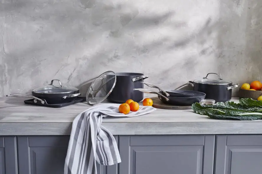 Image of GreenPan Valencia Pro cookware arranged in a gorgeous grey kitchen arranged with some oranges and leafy greens.