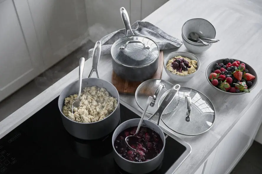 Image of the GreenPan Valencia Pro saucepan set in grey, shown on a stovetop with porridge and berries.