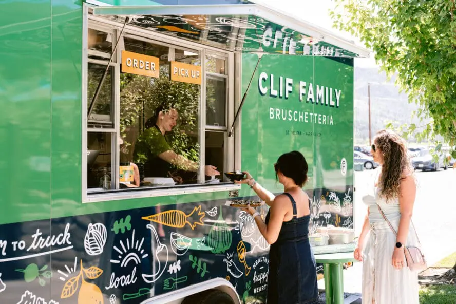 Image of the Clif Family Bruschetteria truck parked outside the winery, with two women standing outside and ordering food.