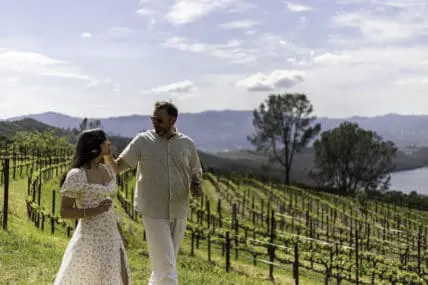 Image of an attractive couple standing in front of the vineyards at the Four Seasons Resort Napa Valley.