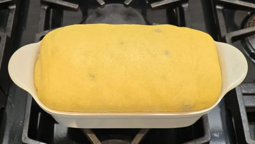 Image of a proofed loaf of brioche rising in an Our Place loaf pan on a stovetop.
