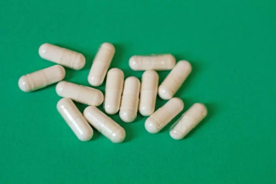 Image of several soluble fiber supplement pills set on a green background.