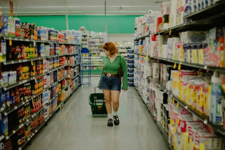 Image of a young woman with a shopping basket in the aisles of a Walmart superstore.