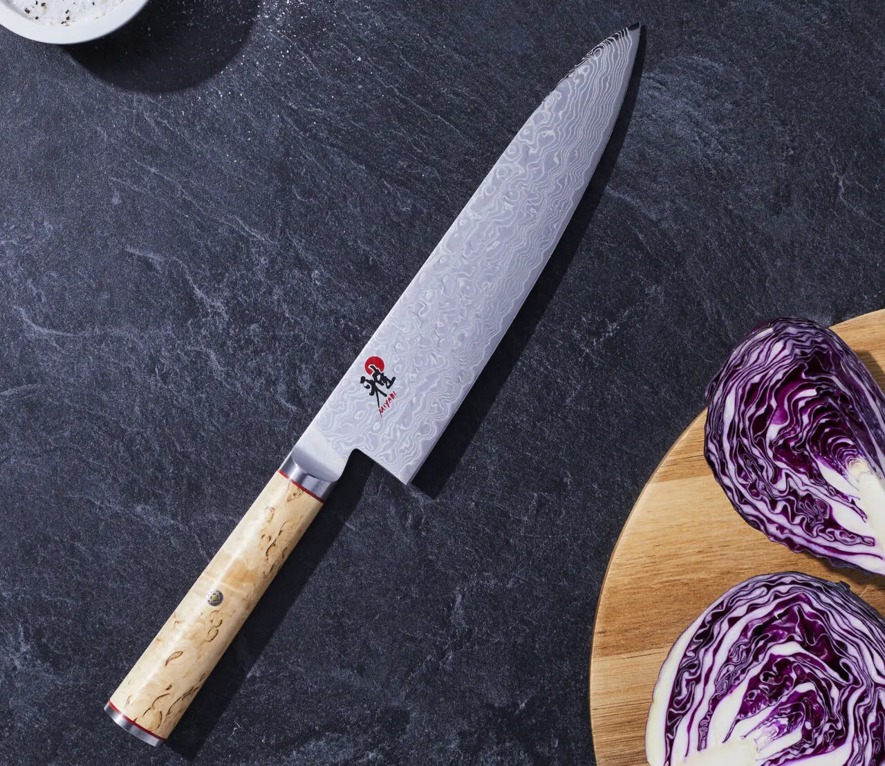 Image of the Miyabi Birchwood 8-in. Chef's Knife displayed next to a cutting board with some purple cabbage.