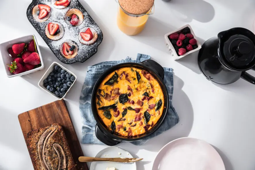 Image of several Xtrema pieces shown on a large table spread, being used to cook a frittata and breakfast muffins.