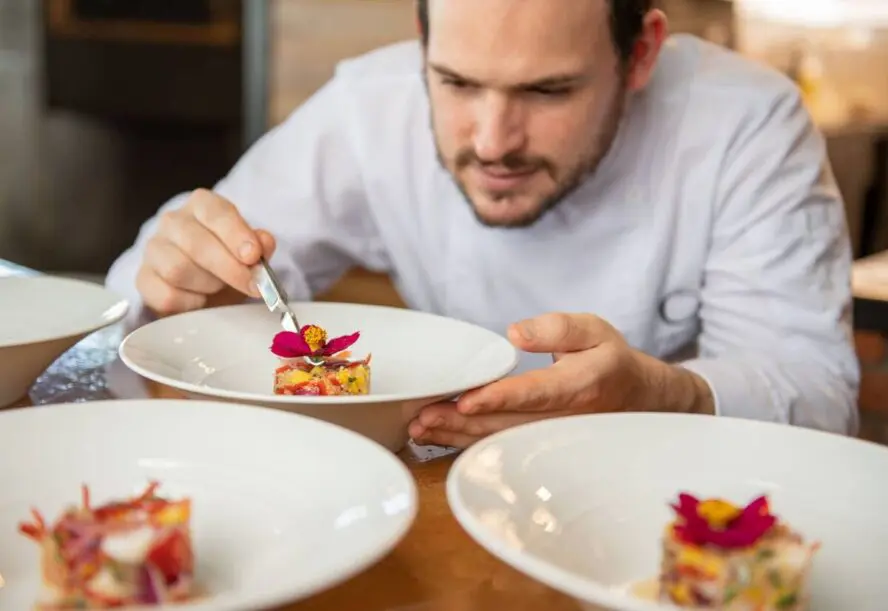 Image of a chef preparing dishes at El Salto Restaurant at Origins Floral Luxury Lodge.