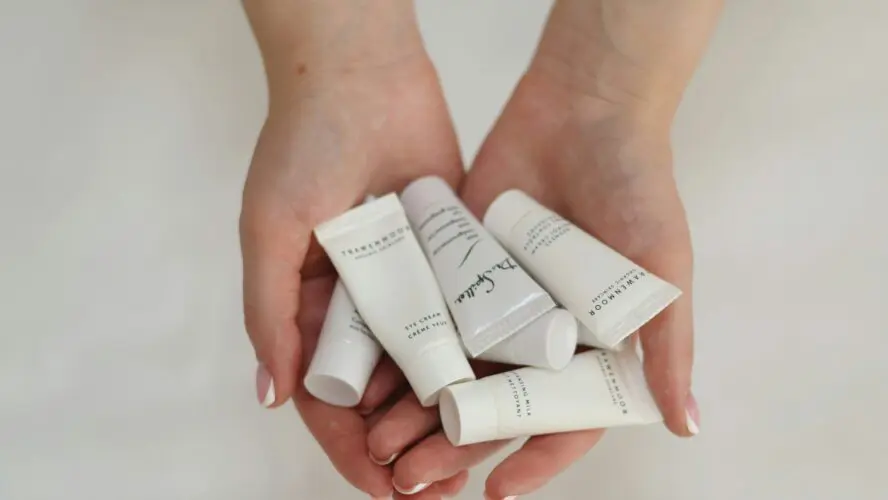 Image of a woman's hans holding travel shampoo bottles of which may contain phthalates. anna keibalo nbiIuy unsplash