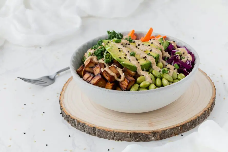 Image of a large white bowl full of salad, including avocado, green beans, tofu, and more vegetables.
