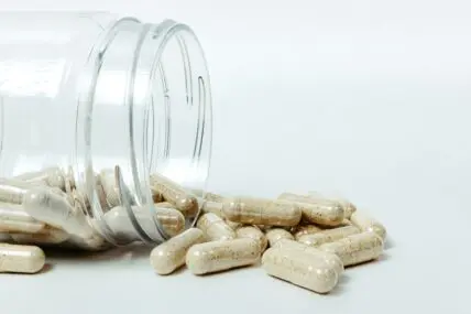 Image of a plastic jar overflowing with little probiotic supplement pills.
