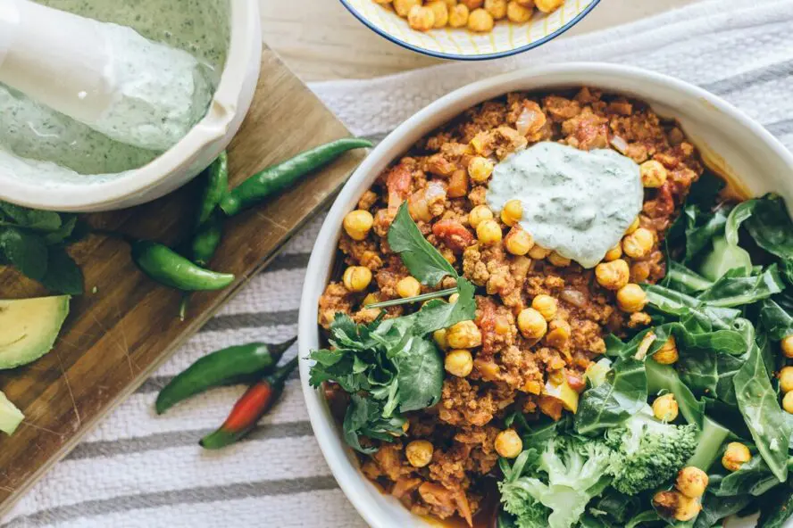 Image of a bowl of a curry-like stew with chickpeas, broccoli, and chili peppers.
