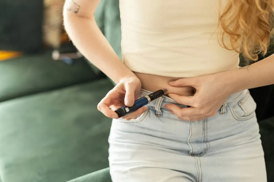 Image of a young woman injecting a GLP-1 medication into her stomach.