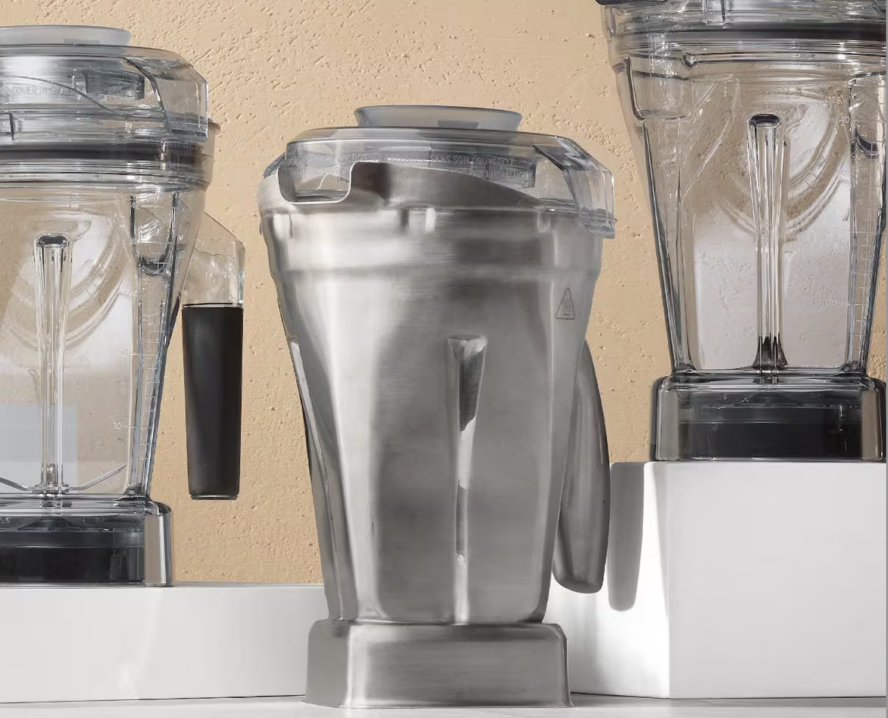 Image of three Vitamix blender jars, with the stainless steel jar in the center.