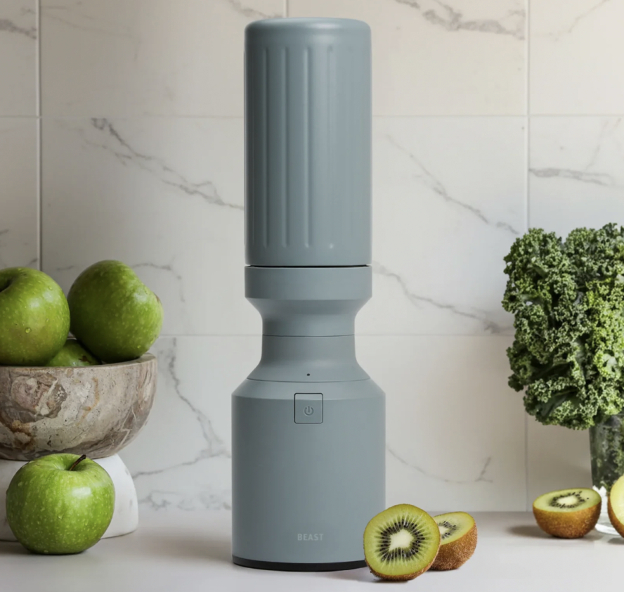 Image of the Beast Mini Stainless Steel Blender in Sage shown on a counter next to fresh fruits.