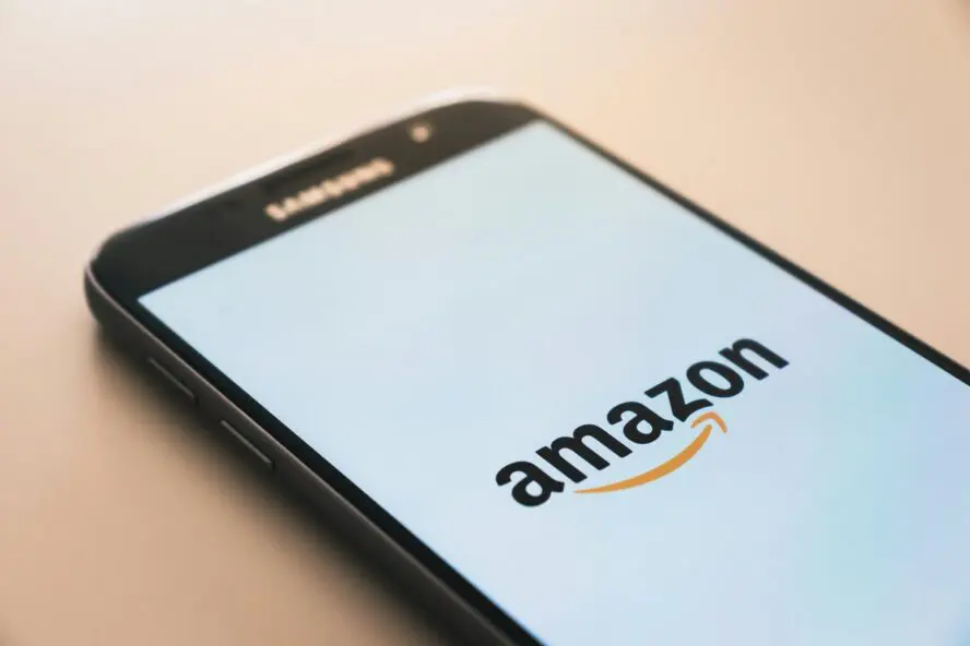 Image of a Samsung phone face up on a wooden table featuring the Amazon logo.