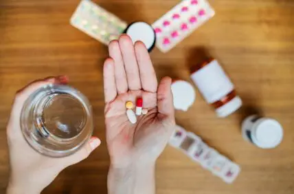Image of a hand with a palm open and several different supplement pills in it.