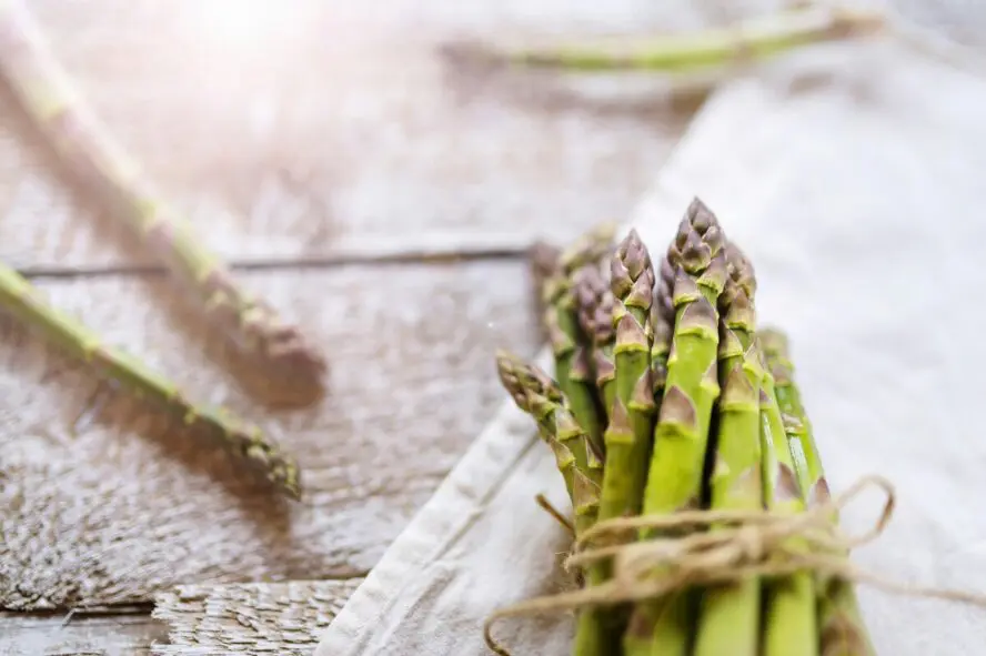 Image of a bunch of asparagus shot on a rustic wooden table.