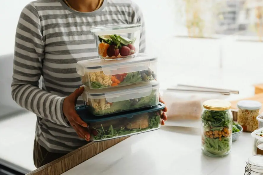 Image of a woman holding a stack of food storage containers filled with meals for the week.