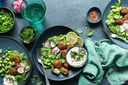 A generous plate of falafel salad with a side of tzatziki in a bowl.