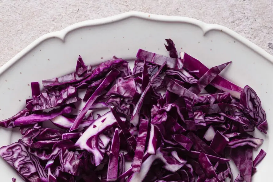 Image of a plate full of sliced purple cabbage for slaw.