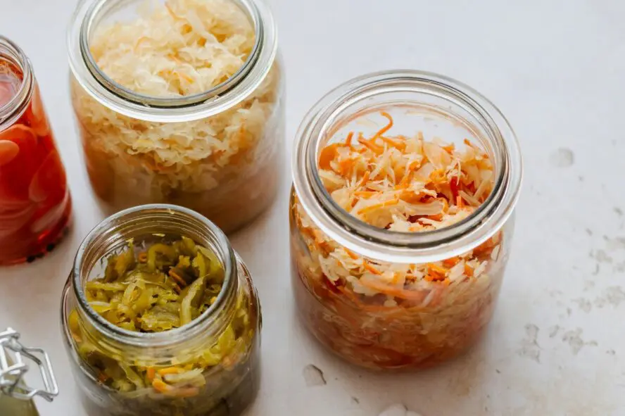 Image of several jars filled with colorful fermented foods, like cabbages and slaws.
