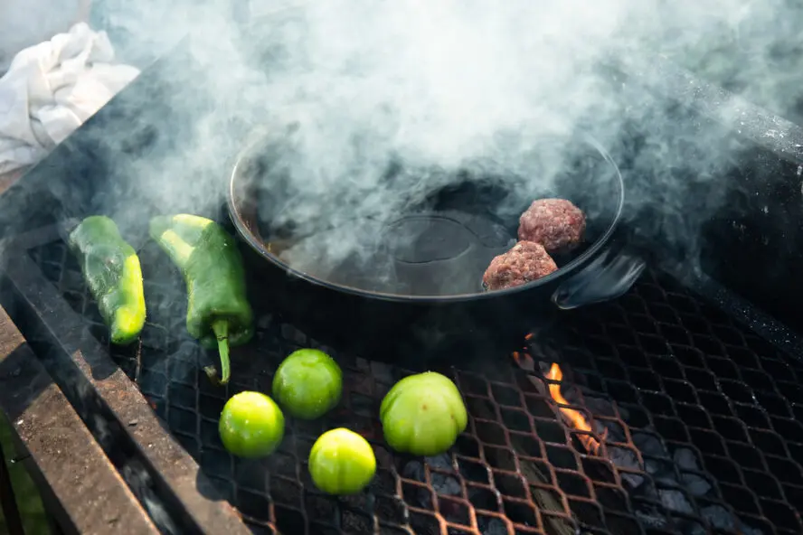 Image of an Xtrema pure ceramic skillet shown on a BBQ grill, being used to cook burgers.