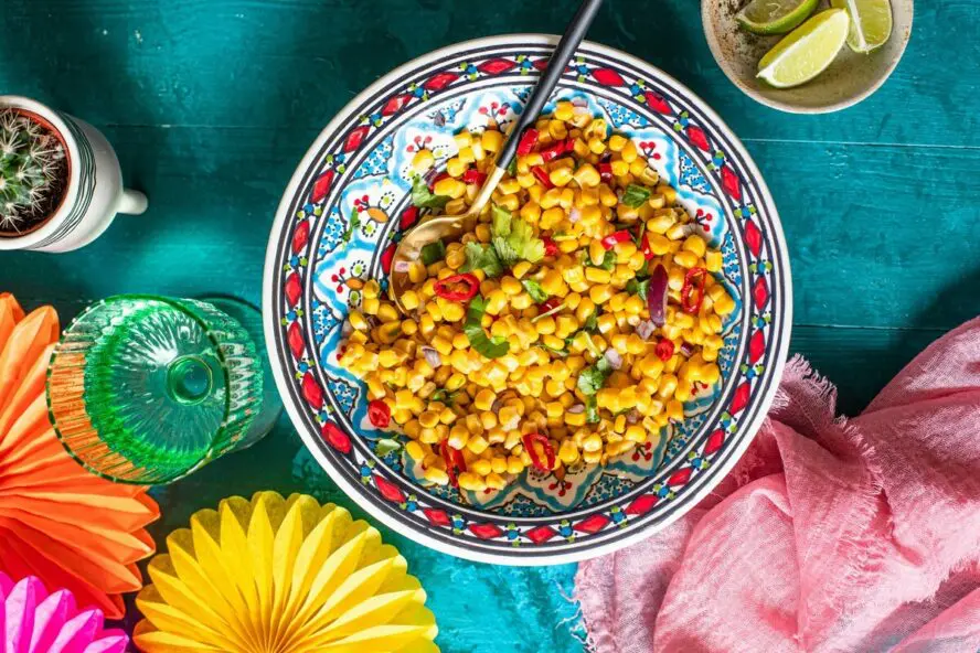Image of a colorful bowl full of roasted corn kernels in a spicy salad.