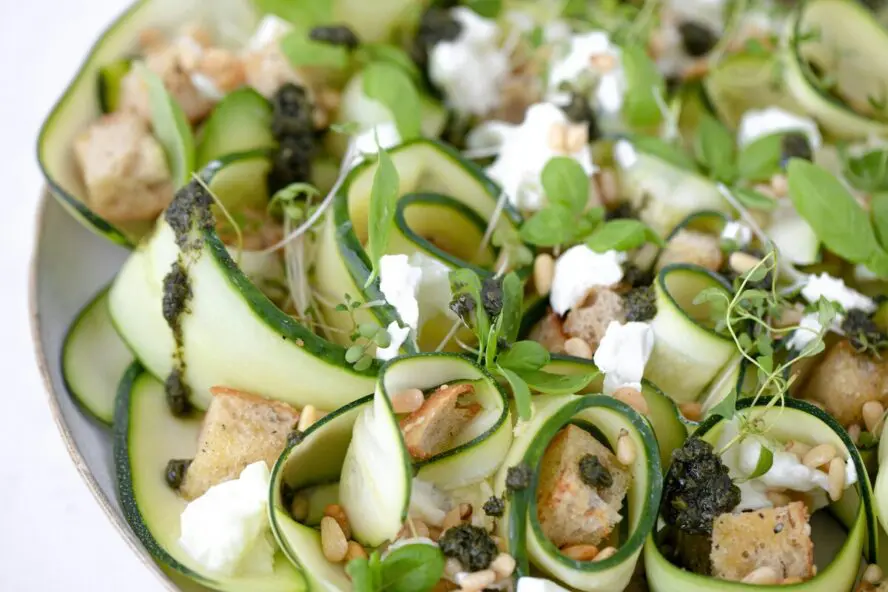 Image of curled up ribbons of zucchini shown in a salad with feta and balsamic dressing.