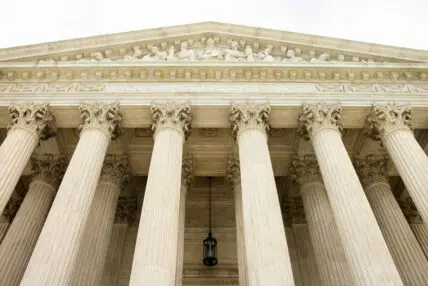 Image of a large judicial building with classic columns, shot from the ground up.
