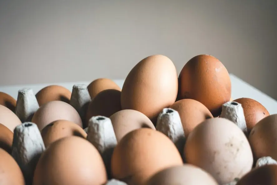 Image of a pile of brown eggs spilling out over their carton.