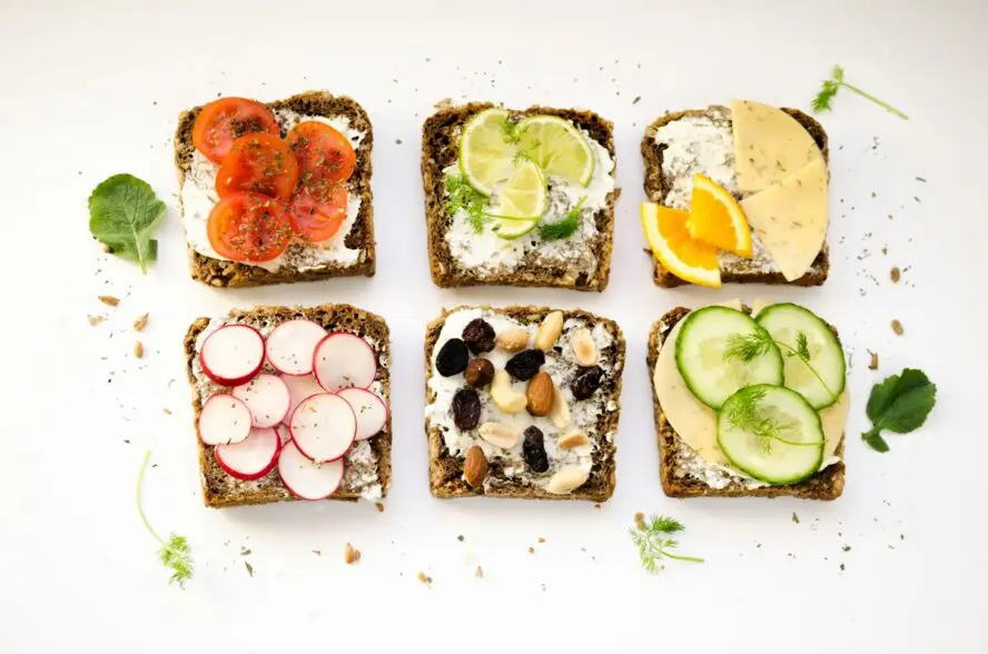 Image of six slices of brown toast topped with cottage cheese and various toppings, from lime to cheese and tomatoes.