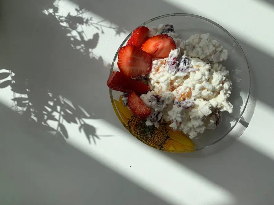 Image of a plate of cottage cheese mixed up with berries and honey.
