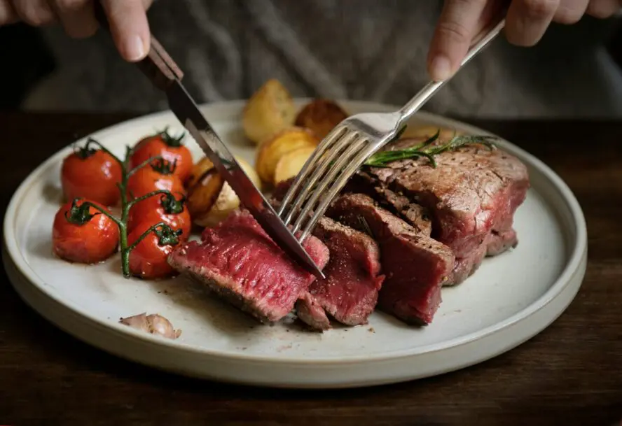 Image of a plate with sliced steak next to roasted cherry tomatoes.