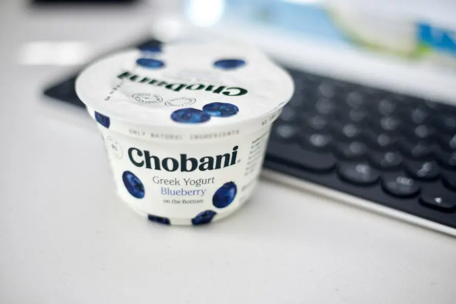 Image of a Chobani blueberry Greek yogurt cup on a desk next to a keyboard.
