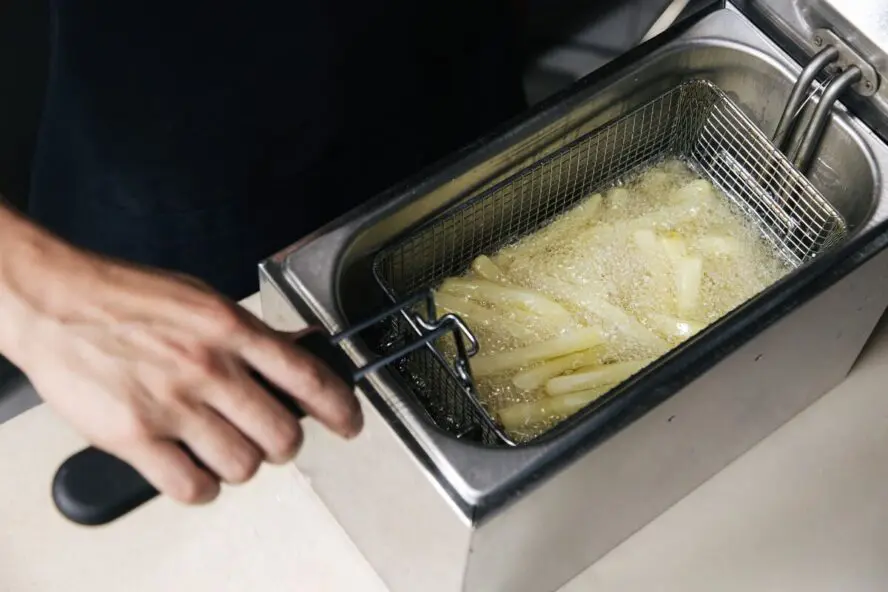 Image of French fries being put into a deep fryer full of beef tallow.