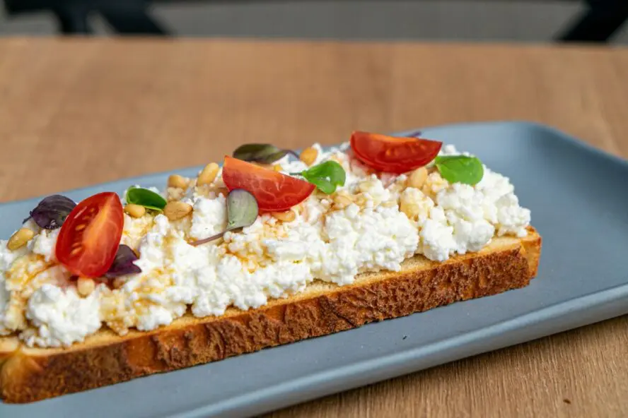 Image of a slice of rye toast topped with cottage cheese and cherry tomatoes.