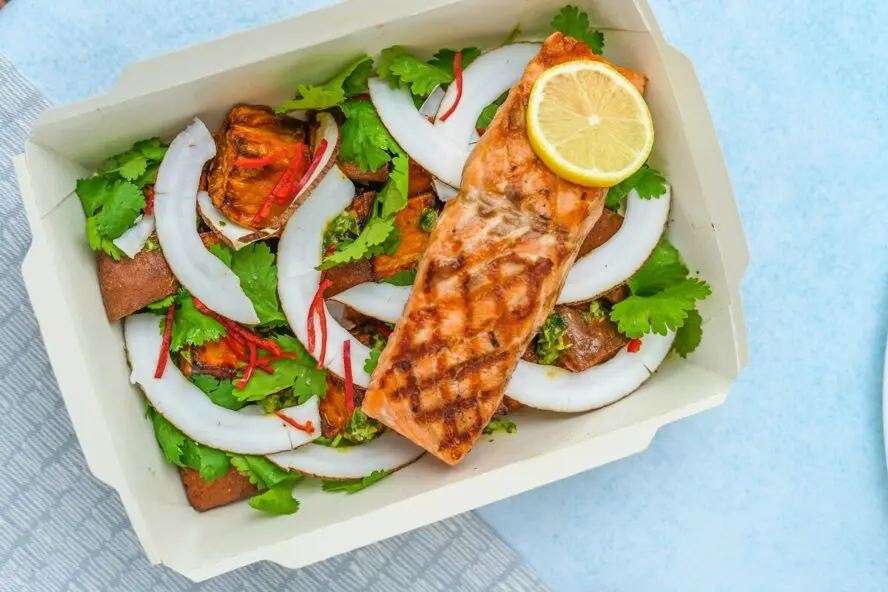 Image of a box filled with a salad, featuring grilled salmon, fennel, lemon, and more.