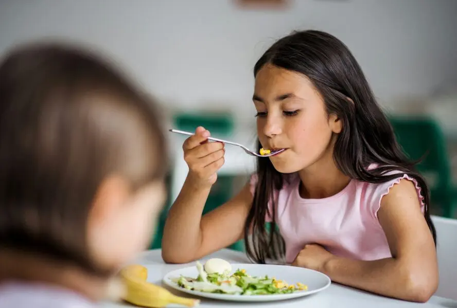 Image of a young girl eating from a plate.