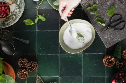 Image of a beautiful tablescape showcasing a bowl of sucralose with a spoon and a hand reaching into the bowl.