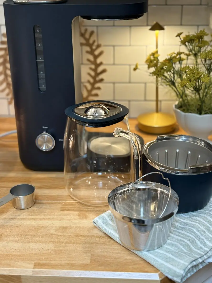 Caraway's new coffee maker on home kitchen counter showing brew basket, reusable stainless steel filter, and glass carafe all made without plastic