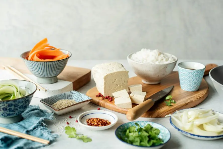 Image of a beautiful spread of food centered around a large slab of tofu.