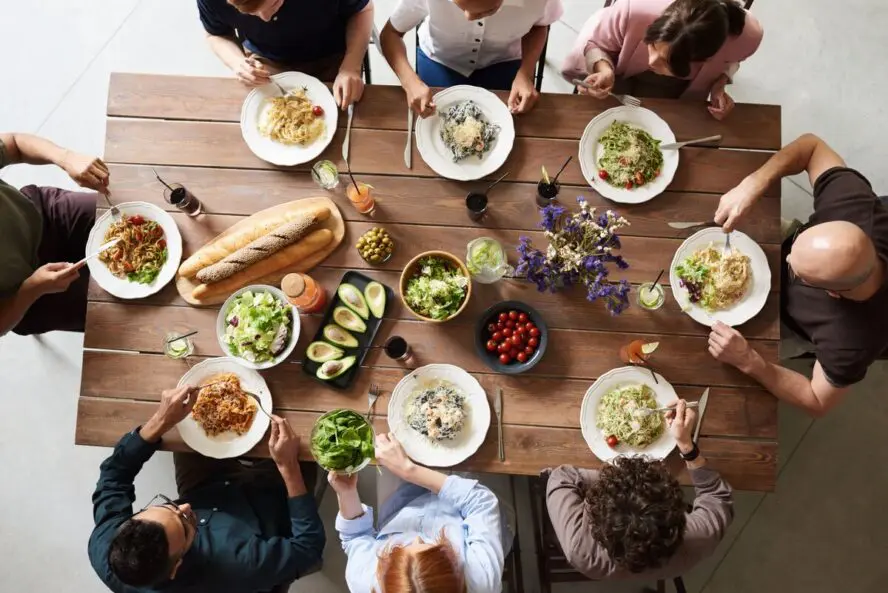 Image of a dining table shot from above, with several people sitting around it sharing a healthy meal.