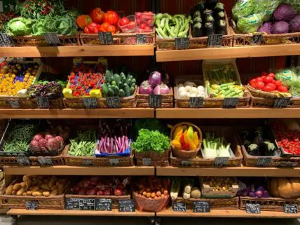 Image of several rows of wooden boxes full of fresh produce, which may be covered in pesticides.