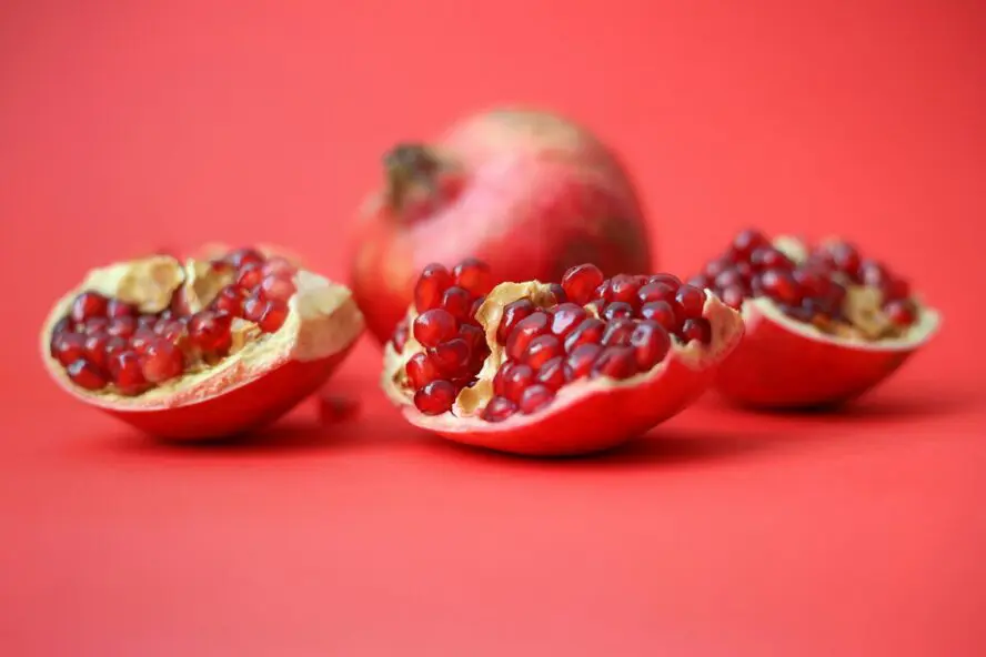Image of a pomegranate fruit, broken open and set against a red background.