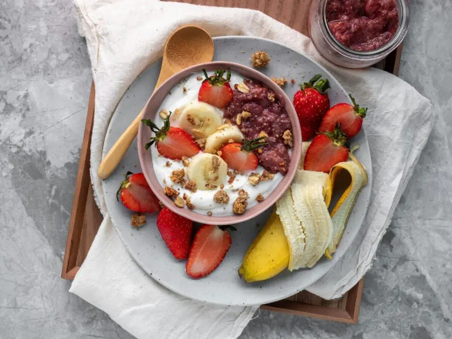 Image of a bowl of yogurt topped with slices of strawberries, bananas, and chunks of granola.