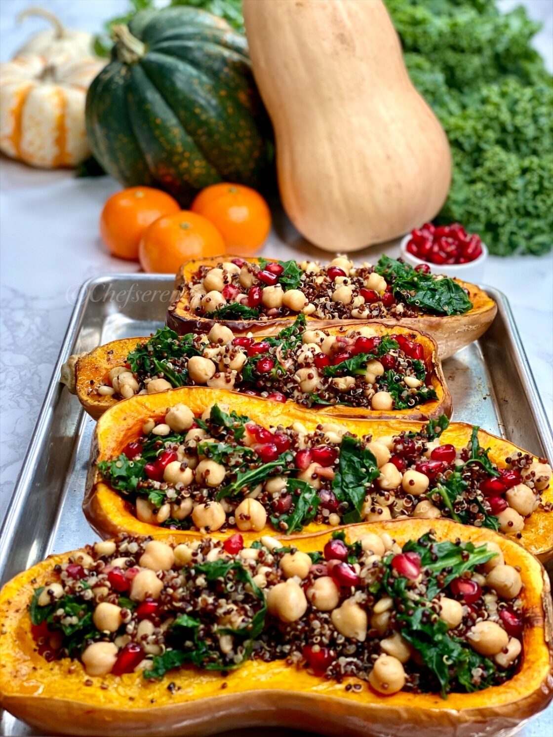 vegetarian stuffed butternut squash on a baking sheet with vibrant produce in the background