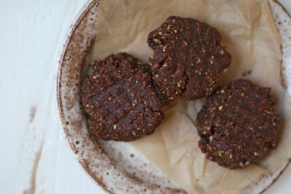 Image of no-bake peanut butter cookies with chocolate on a plate with a torn piece of unbleached parchment paper.