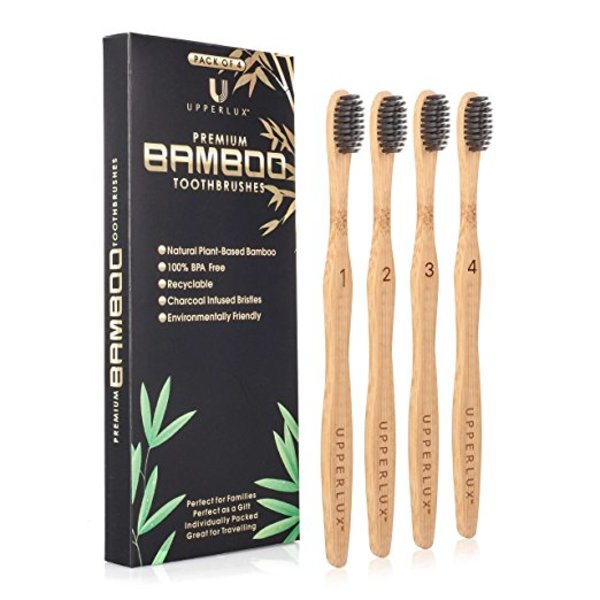 Set of four bamboo toothbrushes with charcoal bristles in packaging