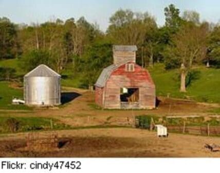 Red barn with metal grain silo on rural farm with fenced pasture