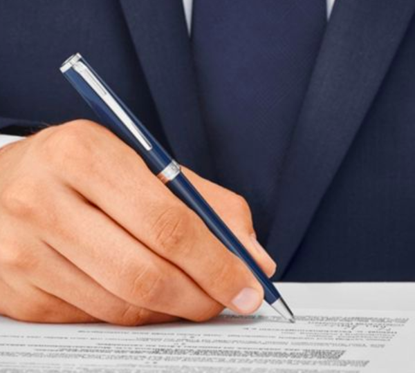Man in business suit signing a document with a blue pen