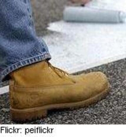 Close-up of a tan Timberland boot worn with jeans on asphalt